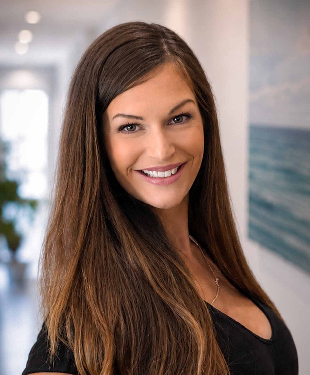 Smiling woman with long hair in modern setting.