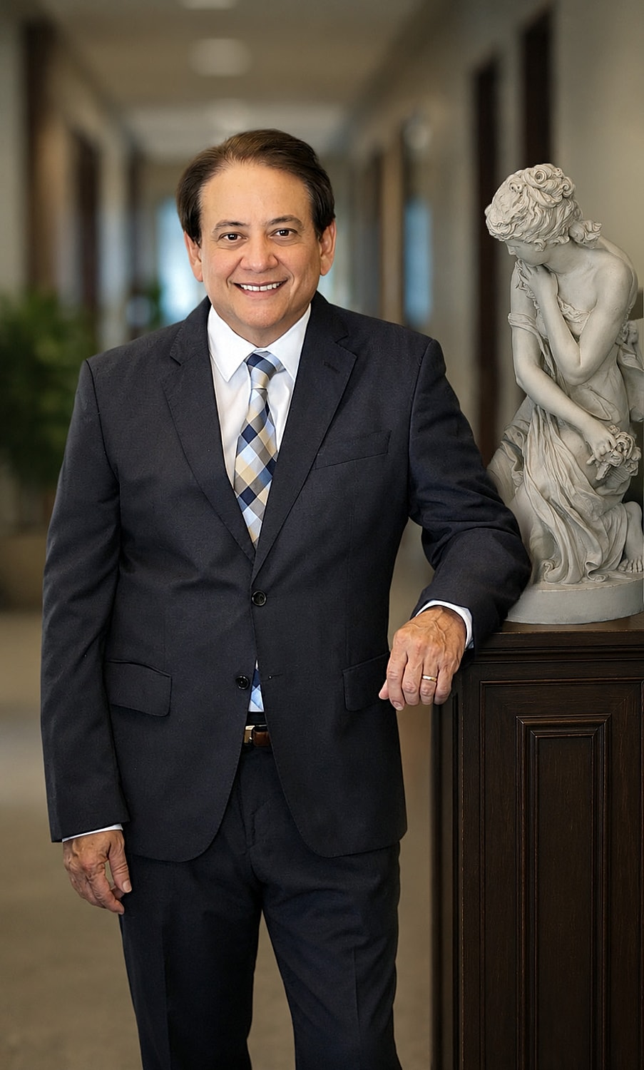 Professional man in suit beside a sculpture.