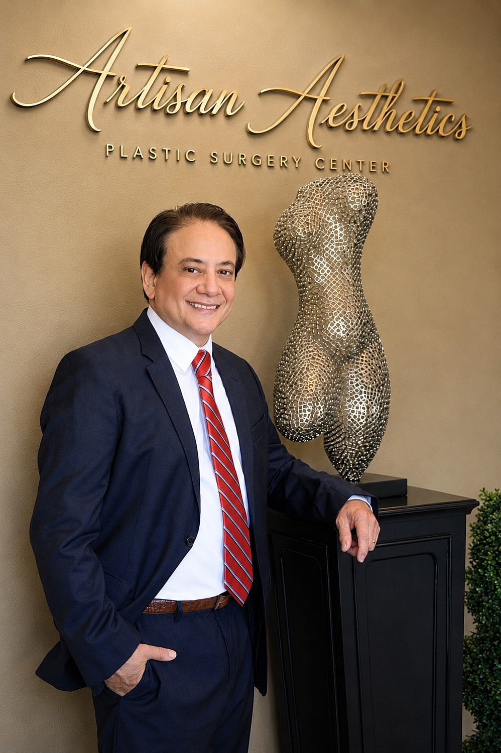 Doctor posing by sculpture at plastic surgery center.
